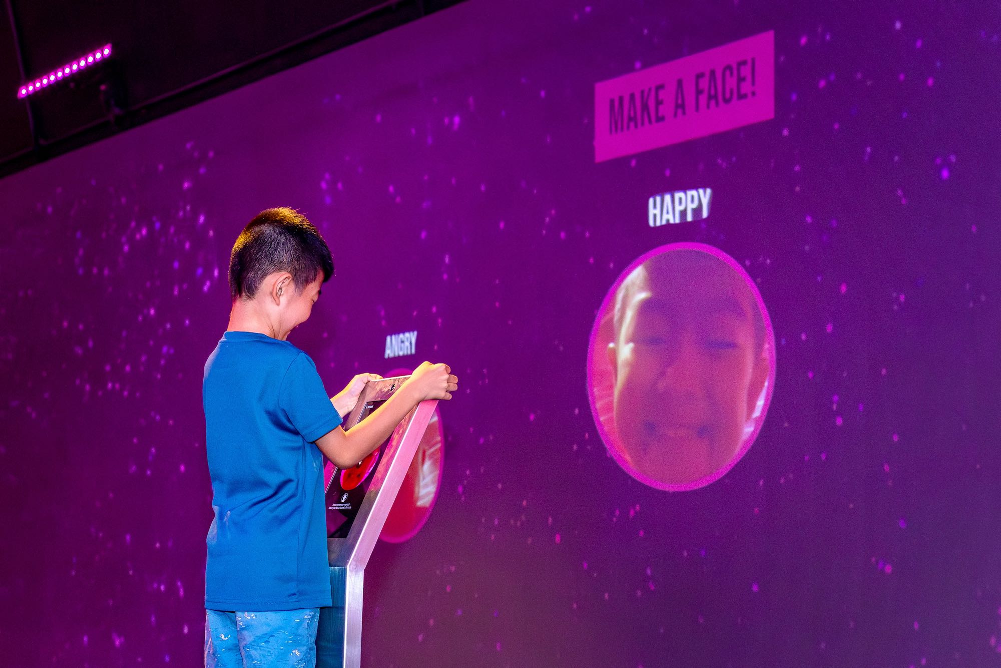 Boy smiling into a tablet, projected on a big screen